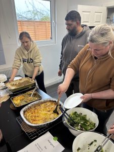 People helping themselves to food at buffet.